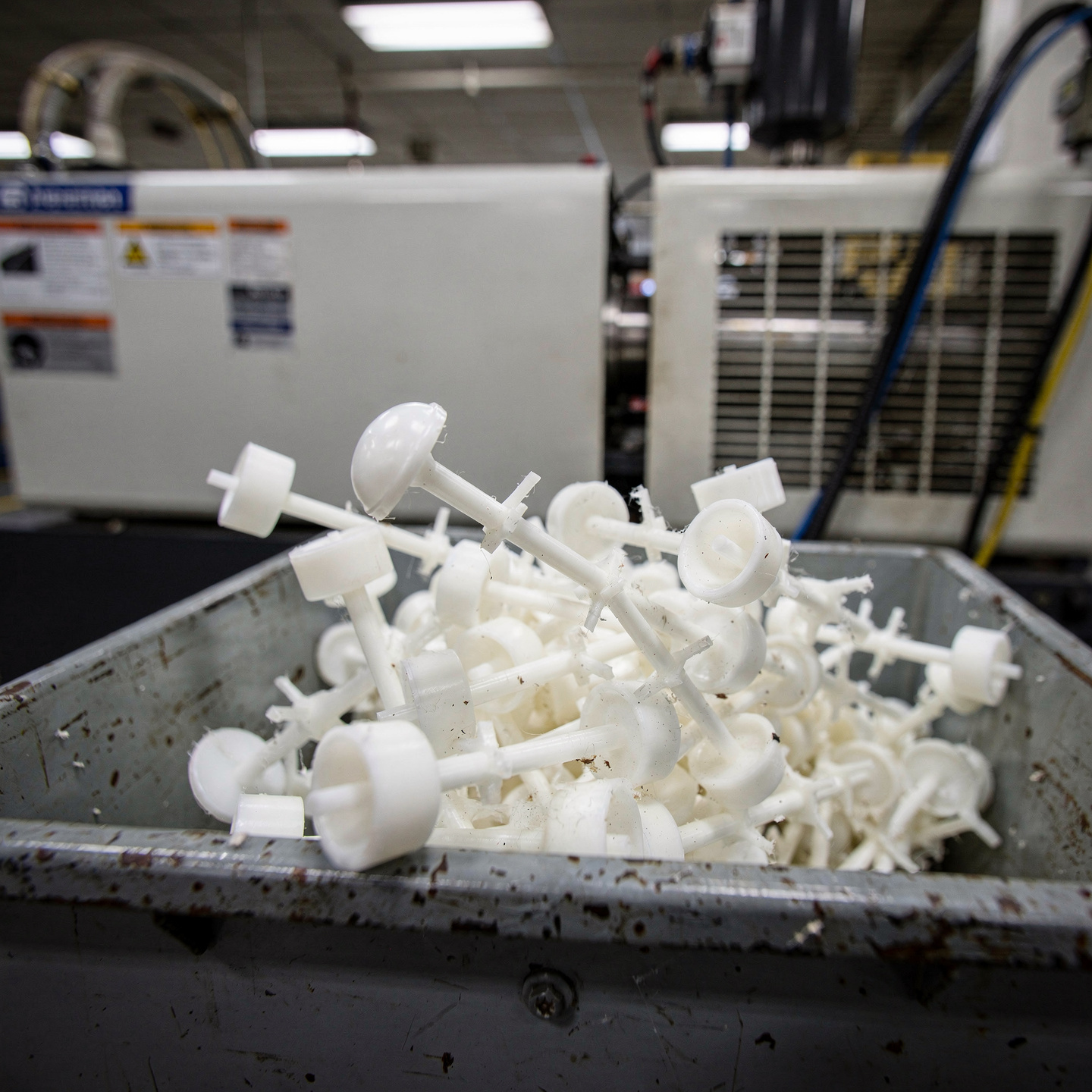 Freshly injection-molded plastic parts attached to their sprue in a collection bin