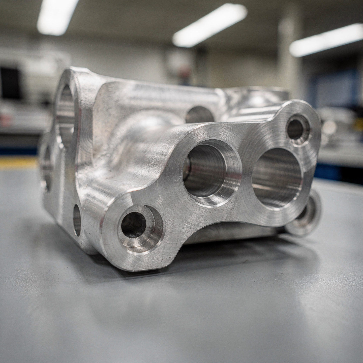 Machined aluminum bracket with angled bores and compound curved surfaces on multiple faces